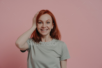 Portrait of excited amazed redhead ginger girl touching head with surprised facial expression