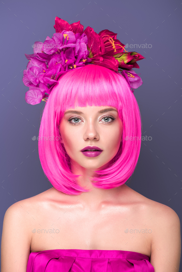 close-up portrait of beautiful young woman with pink bob cut and flowers in hair looking at camera