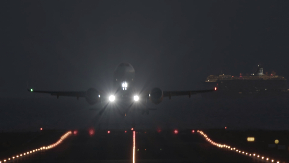 Airplane Takeoff at Night with a Passing Cruise Ship in the Background alt