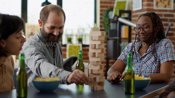 Male player losing at society game with wooden tower on table