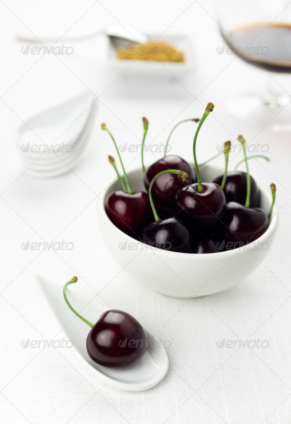 Cherries on white spoon and bowl, sherry glass brown,sugar - Stock Photo - Images