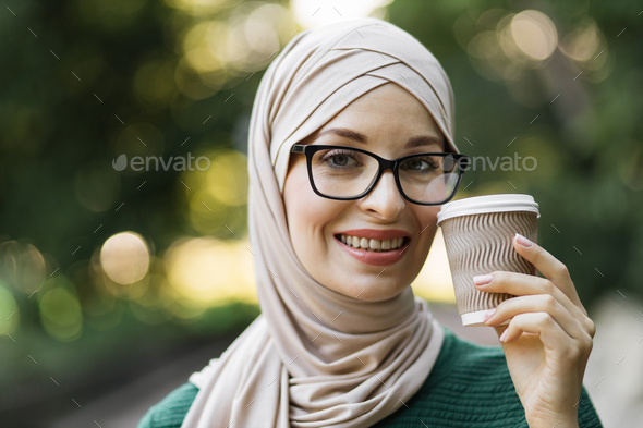 Portrait of young muslim woman wearing hijab head scarf and coffee to ...