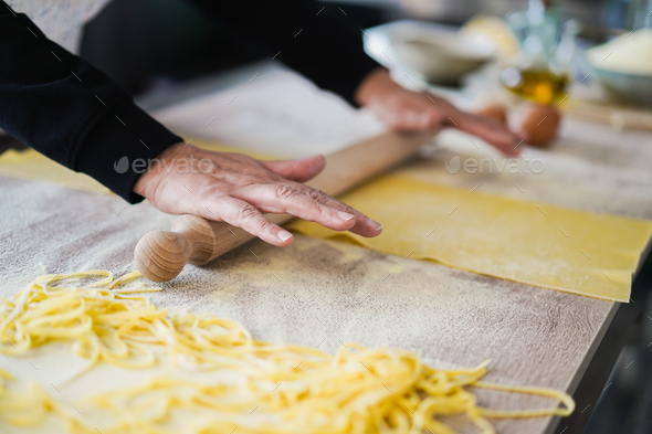 Woman preparing dough for ravioli inside pasta factory - Soft focus on fingers