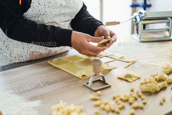 Woman prepare fresh ravioli inside pasta factory - Soft focus on left hand