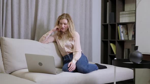 Portrait of young girl with laptop and talking on phone looking at screen. alt