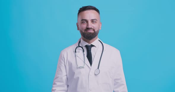 Medical Approval. Cheerful Doctor Gesturing Thumbs Up and Smiling, Blue Studio Background alt