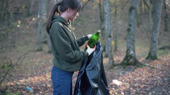 A Young Beautiful Woman Collects a Plastic in the Autumn Forest