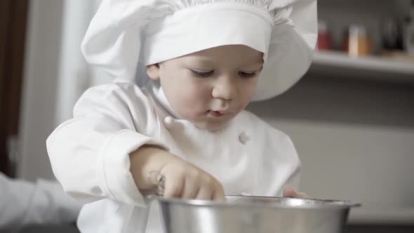 Closeup of a Concentrated Child with Chef Uniform Learning Making Cake