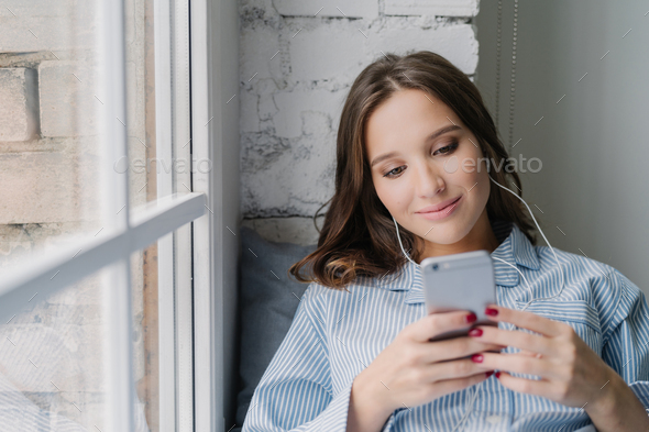 woman creats new playlist on mobile phone, types email and enjoys music in earphones