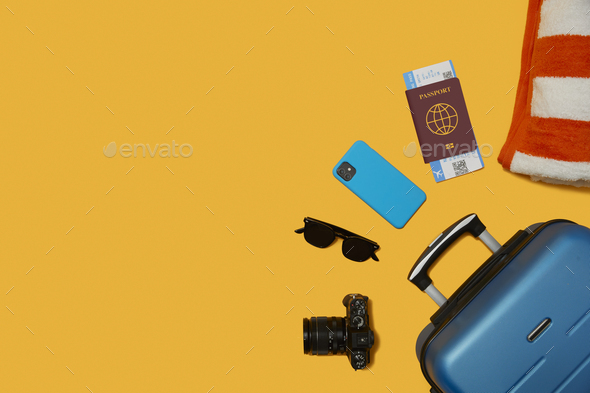 Flat Lay Shot Of Blue Suitcase Unpacked With Holiday Accessories On Yellow Background - Stock Photo - Images