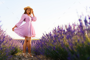 Young woman in a straw hat walking in a lavender field