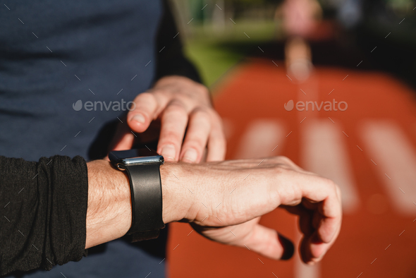 Fitness smart watch. Male runner checking time, physical activity, running distance on armband