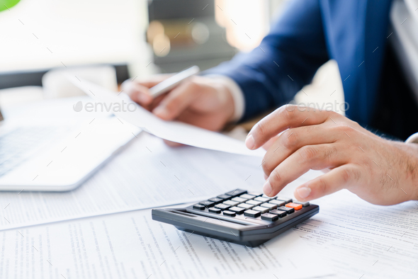 Businessman counting bills savings investments dividends on calculator, managing money - Stock Photo - Images