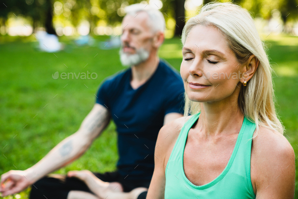 Close Up Portrait Of Mature Caucasian Couple Meditating Together On Fitness Mat In Public Park 9783