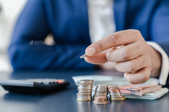 Businessman holding euro cents coins dollar bills on table with pile of coins - Stock Photo - Images