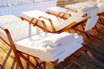 Empty deck chairs with white mattresses in resort hotel