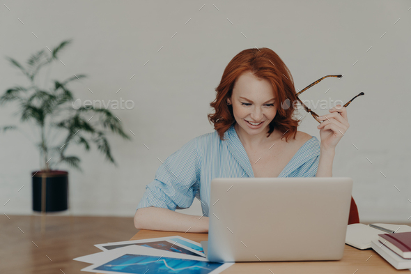 Positive busy woman with European appearance works on freelance digital project