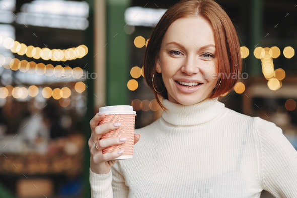Optimistic lovely woman with dyed hair, satisfied expression, wears turtleneck jumper