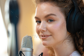 Portrait of happy young female radio host broadcasting in studio