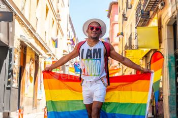 A gay black man walking in the pride party with an LGBT flag visiting the city