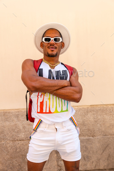 A gay black ethnic man at the pride party on a cream wall, LGBT flag, vertical photo