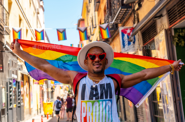 A gay black man enjoying and smiling at the pride party with an LGBT flag