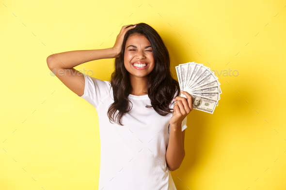 Image of beautiful african-american girl, winning money, smiling happy with eyes closed, feeling