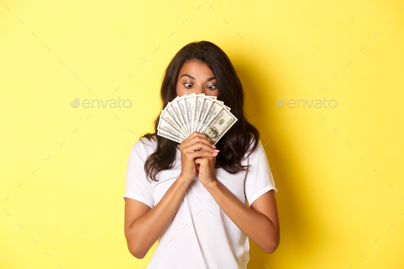 Portrait of lucky african-american girl winning money prize, holding cash and looking amazed