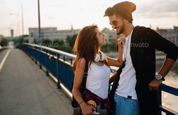 Portrait of happy couple having fun while driving a long board in city. People skateboard concept - Stock Photo - Images