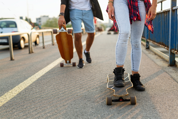 Portrait of happy teenager people having fun while driving a skateboard in city outdoors - Stock Photo - Images