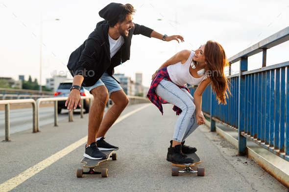 Portrait of happy couple riding skateboards and having fun outdoors. Teenager happiness concept - Stock Photo - Images