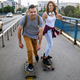 Portrait of happy couple having fun while driving a long board in city. People skateboard concept - PhotoDune Item for Sale