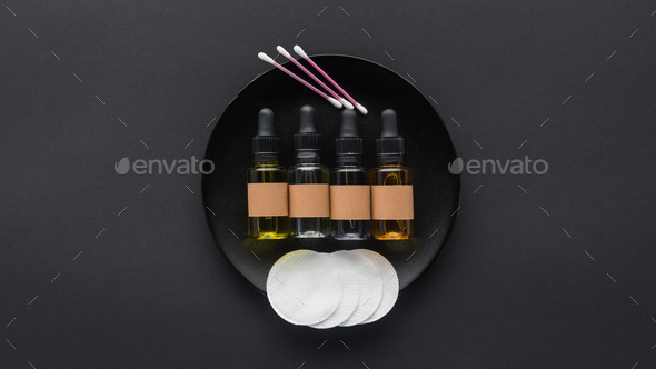 top view of bottles of natural oils and cosmetic pads on plate, beauty concept