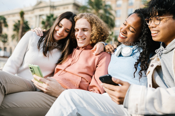 Group of multiracial young friends using cell phones outdoors