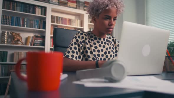 Serious Dark Skinned Woman Typing and Sending Email While Sitting at Laptop alt