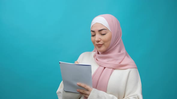 Thoughtful Creative Young Muslim Woman in Hijab Thinking Over Future Business Plan Taking Notes in