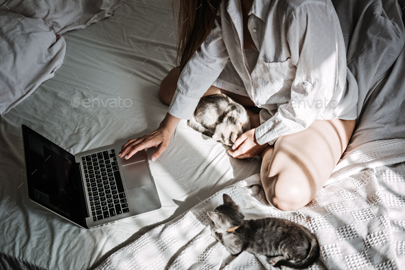 Work From Home Jobs, remote online work, home office. Woman working on laptop in bed