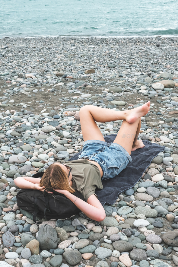 Traveler girl resting on the beach near the sea. Eco travel, taking care of yourself physical and