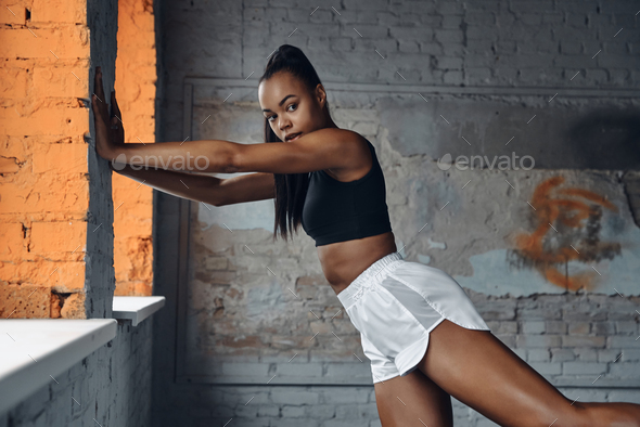 Confident young woman in sports clothing doing stretching