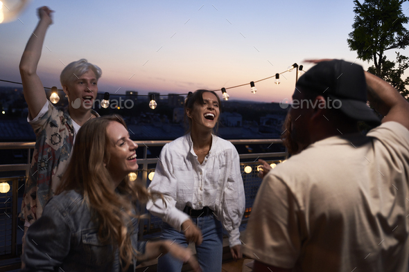 Group of happy friends dancing at the party in top of the roof