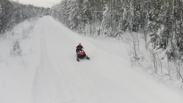 Men on snowmobile having fun and riding in winter scenery. Clip. Aerial view a man on red snowmobile alt