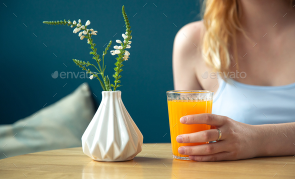 A glass of orange juice on a table in a blue interior. Stock Photo by  puhimec