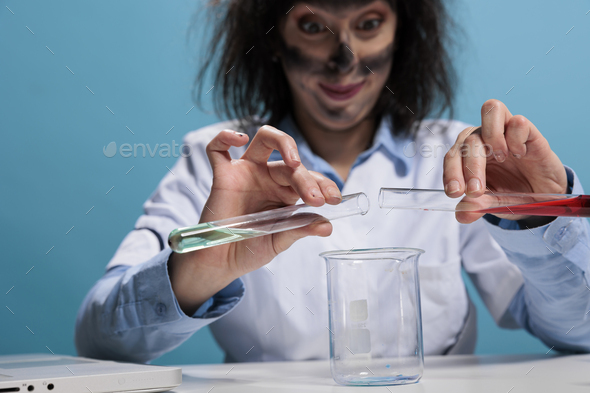 Close up of mad foolish scientist testing experimental serum by adding unknown substance while on