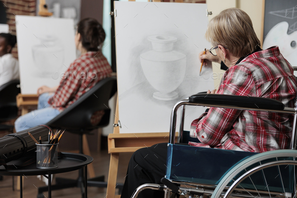 Senior woman in wheelchair attenting art class for rehab drawing vase sketch