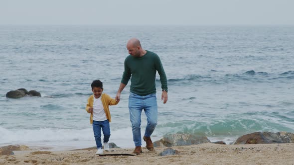 Father Is Walking With Small Son On Ocean Beach