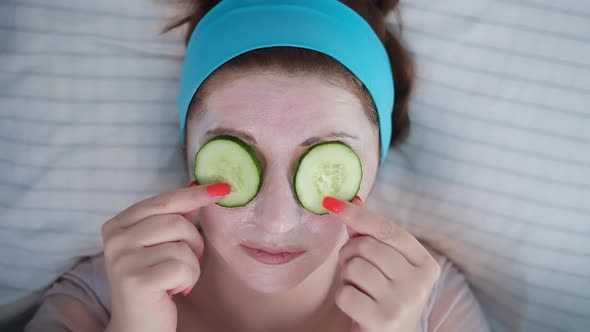 Pretty Woman Puts Cucumbers on Her Eyes Cosmetic Mask Skin Care Lying on the Bed