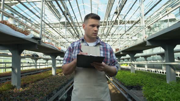 Busy Young Farmer Writing Calculations in Document, Preparing Order for Customer