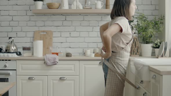 Woman in the Kitchen Putting on an Apron