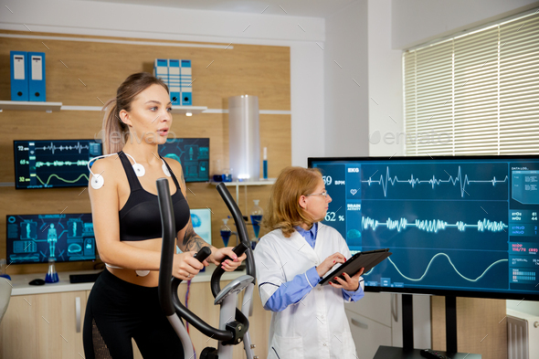 Fit female testing the stepper with electrodes on it and the doctor ...