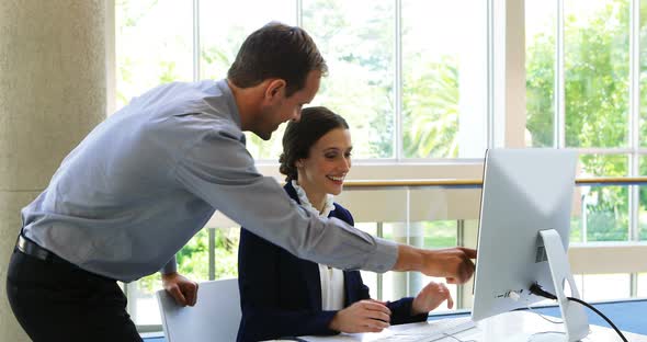 Business colleagues discussing over computer at desk 4k alt